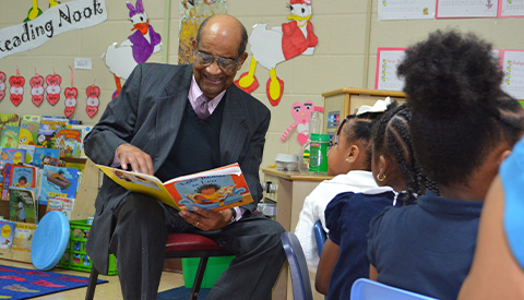man reading a book to children
